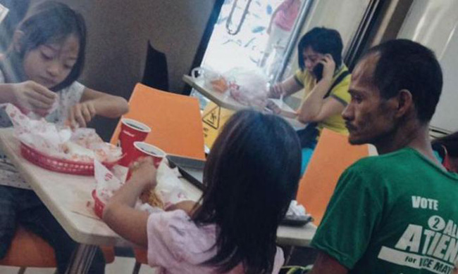 Hình ảnh người cha khắc khổ lặng lẽ nhìn 2 con gái nhỏ say sưa ăn gà rán khiến nhiều người rơi nước mắt